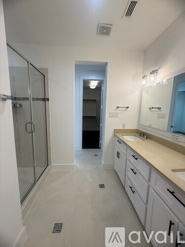 A bathroom with a glass shower door and a sink with a countertop.