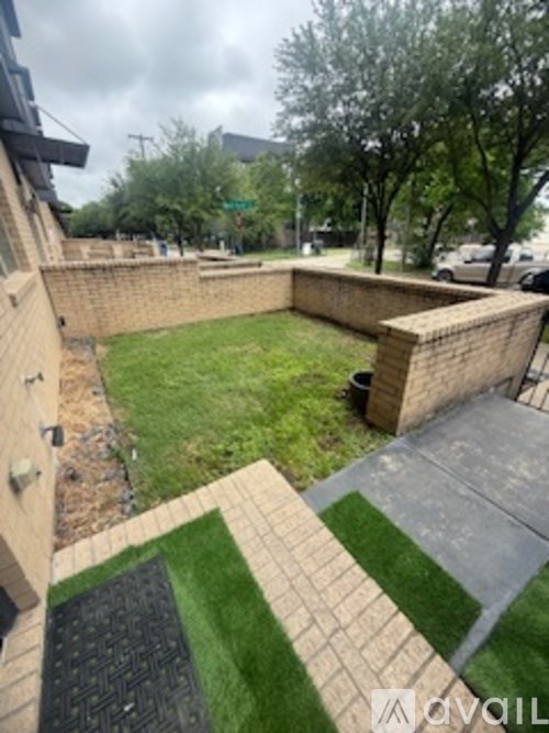 A backyard with a brick wall and a green lawn.