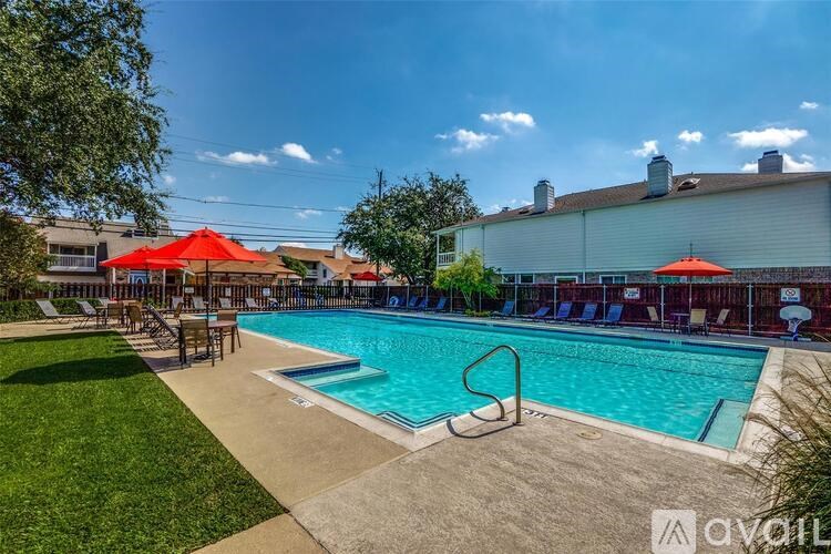 A pool with a red umbrella and chairs is surrounded by a grassy area.