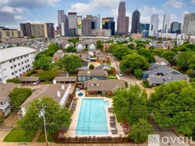 A bird's eye view of a swimming pool surrounded by trees and buildings in the distance.