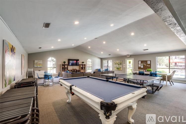 A billiards table is in the middle of a room with chairs and a TV.