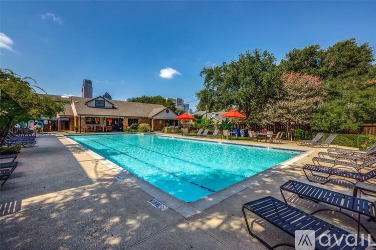 A large outdoor swimming pool surrounded by lounge chairs and trees.