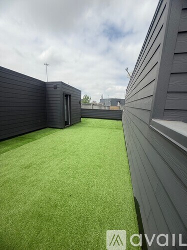A backyard with a green lawn and a grey fence.