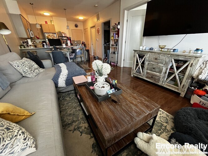 A living room with a grey couch, a coffee table, and a wooden cabinet.