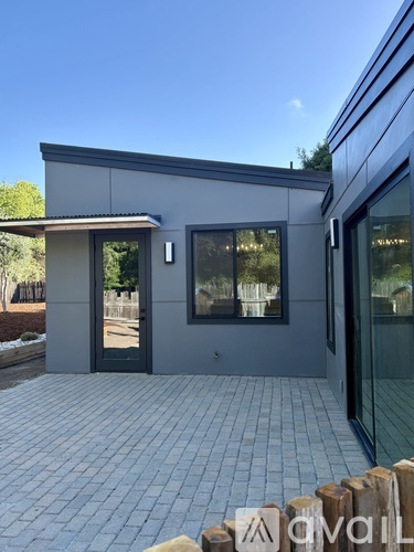 A modern house with a grey exterior and a tiled patio.