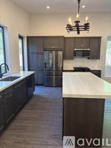 A kitchen with a white counter top and dark wood cabinets.