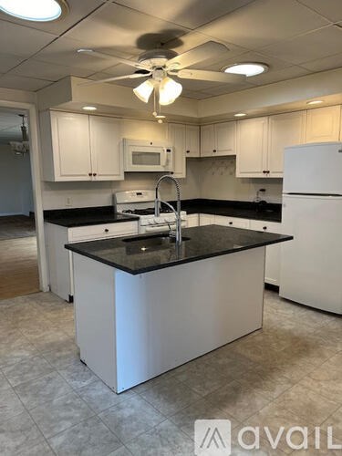 A kitchen with white cabinets and a black countertop.