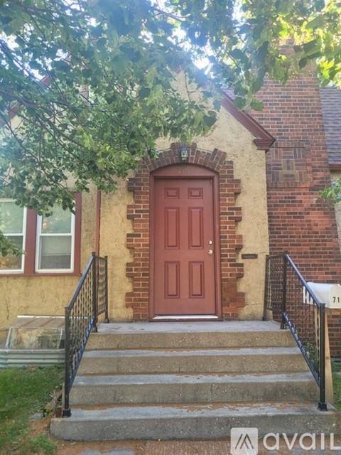 A red door is on the front of a brick house.
