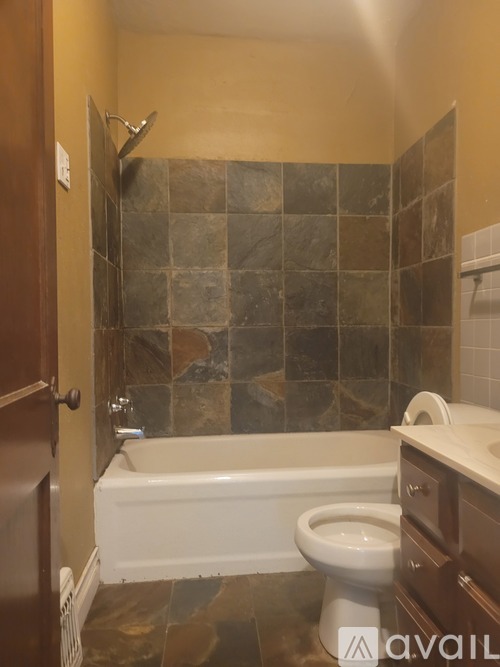A bathroom with a toilet, tub, and tiled walls.