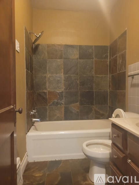 A bathroom with a toilet, tub, and tiled walls.
