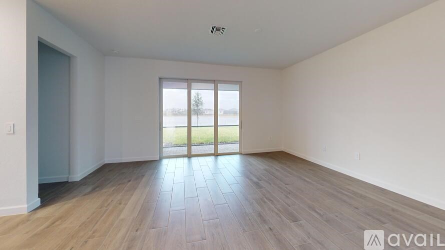 A spacious room with wooden flooring and a sliding glass door leading outside.