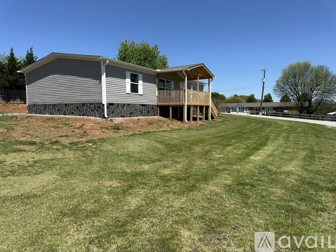 A house with a grey siding and a wooden deck is available for sale.