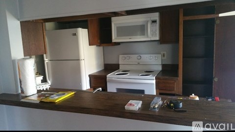 A kitchen with a white refrigerator, a white microwave, a white stove, and a wooden counter.