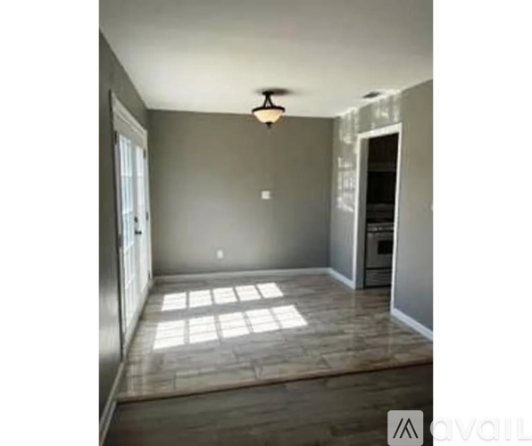 A room with a wooden floor and a window letting in sunlight.
