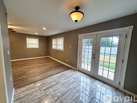 A room with wooden flooring and two windows.