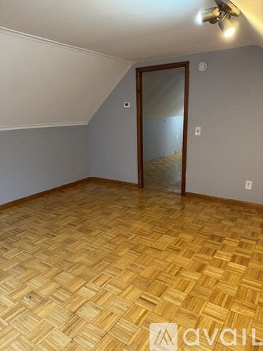 A room with wooden flooring and a door leading to another room.