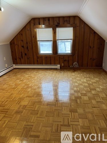 A room with wooden walls and a wooden floor with a window.