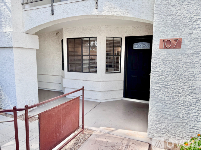 A white building with a black door and a red gate.