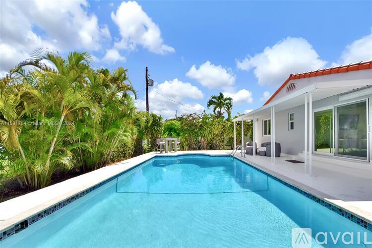 A swimming pool in a backyard with a house and palm trees in the background.