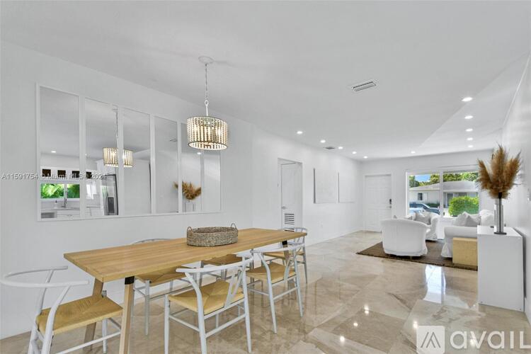 A modern dining room with a wooden table and white chairs.