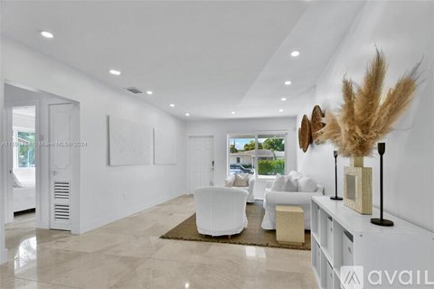 A modern living room with white furniture and a large window.