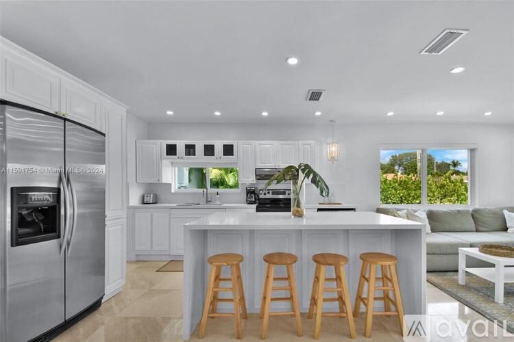 A modern kitchen with white cabinets and a central island with bar stools.
