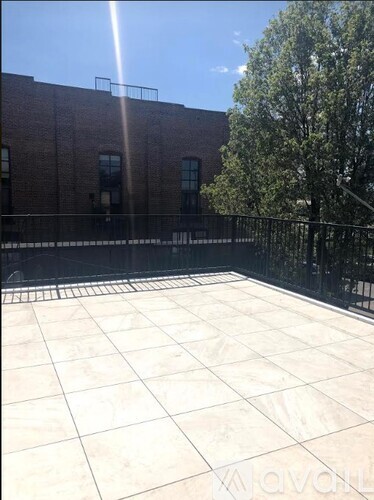 A sunny day at a courtyard with a black fence and a brick building.