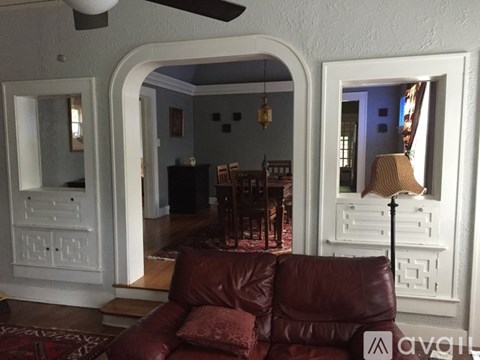 A living room with a brown leather couch and a ceiling fan.