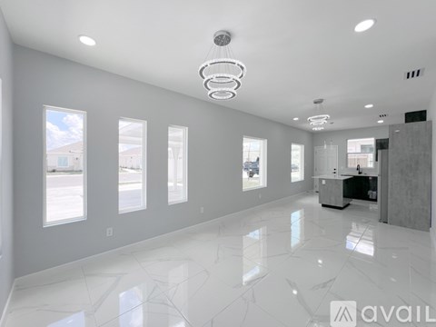 A spacious, well-lit room with a marble floor and a large mirror on the wall.