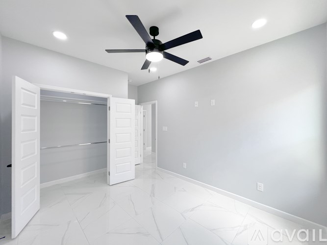 A spacious room with a ceiling fan and white walls.