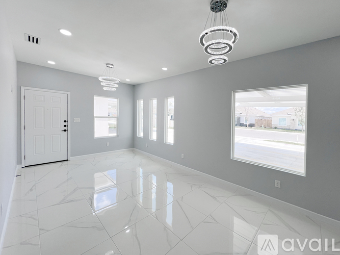 A spacious room with white marble flooring and a large window.