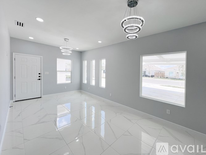 A spacious room with white marble flooring and a large window.