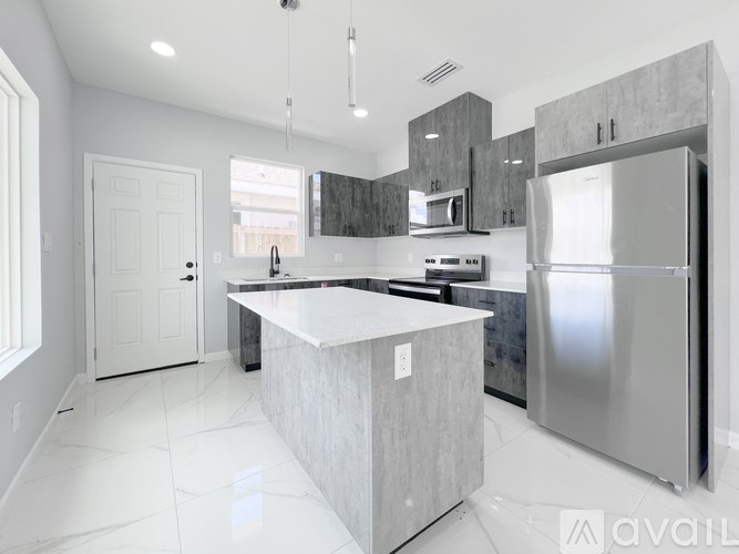 A modern kitchen with a large island and stainless steel appliances.