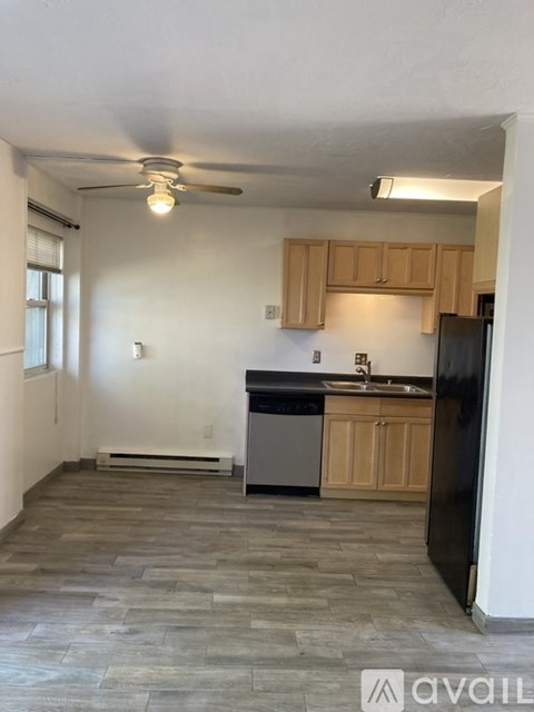 A kitchen with wooden cabinets and a black refrigerator.