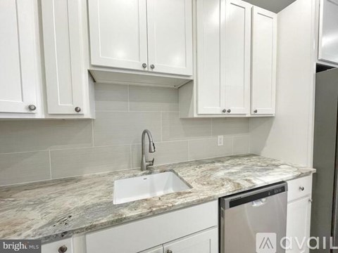 A kitchen with white cabinets and a marble countertop.