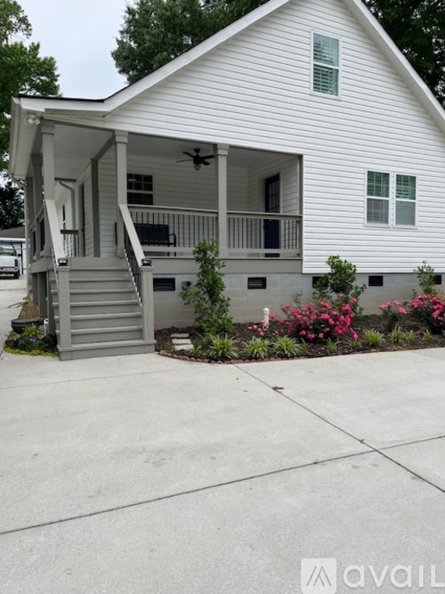 A white house with a porch and a driveway.