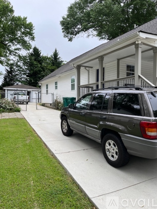 A silver SUV is parked on a driveway in front of a white house.
