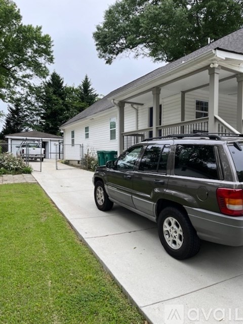 A silver SUV is parked on a driveway in front of a white house.