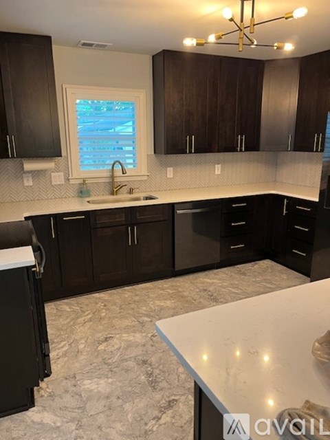 A kitchen with black cabinets and a marble countertop.