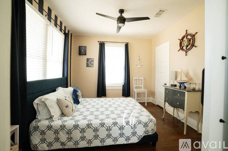 A bedroom with a patterned bedspread and a ceiling fan.