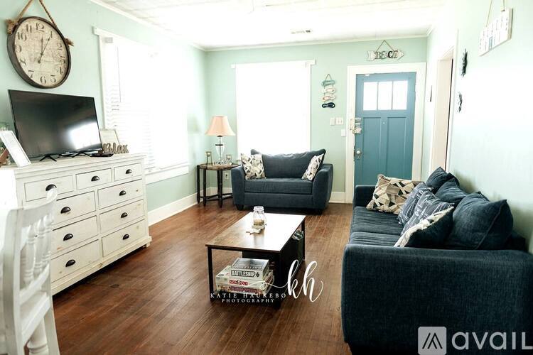 A living room with a black couch, a white dresser, and a wooden floor.