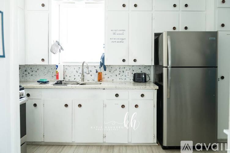 A kitchen with white cabinets and a stainless steel refrigerator.