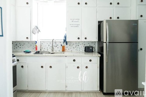 A kitchen with white cabinets and a stainless steel refrigerator.