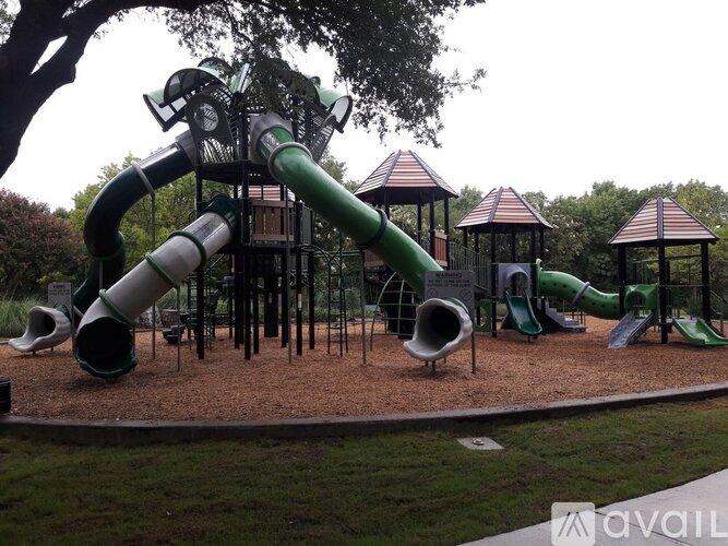 A playground with a green slide and a brownish ground.