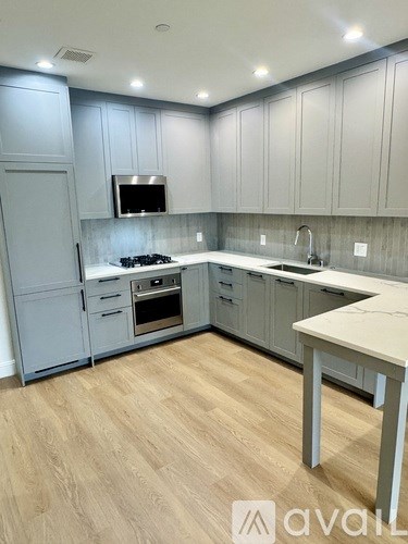 A kitchen with wooden floors and grey cabinets.