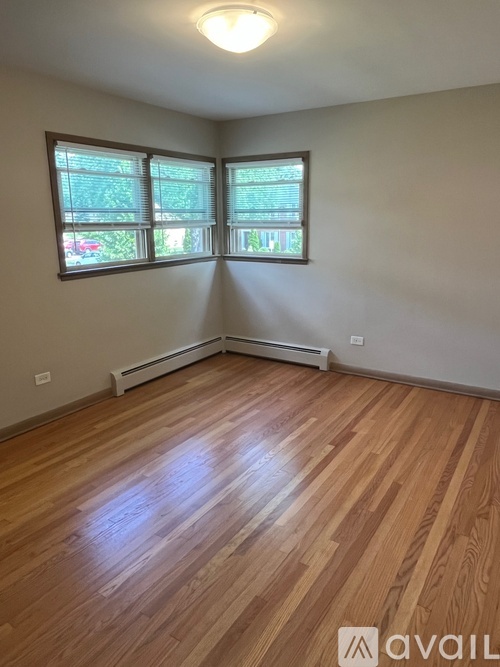A room with wooden flooring and a window with blinds.