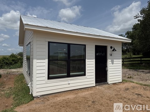 A small white house with a grey door and windows is available for purchase.