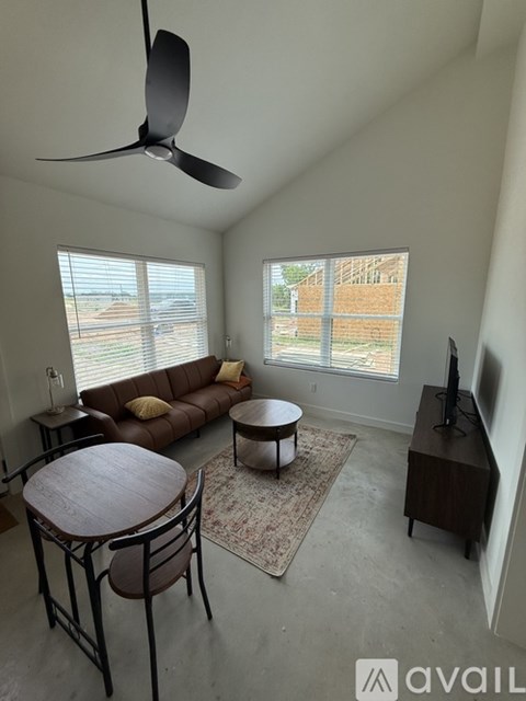 A living room with a brown couch and a ceiling fan.