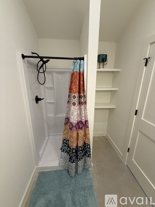 A bathroom with a blue rug and a shower curtain with a pattern of orange, black, and white.
