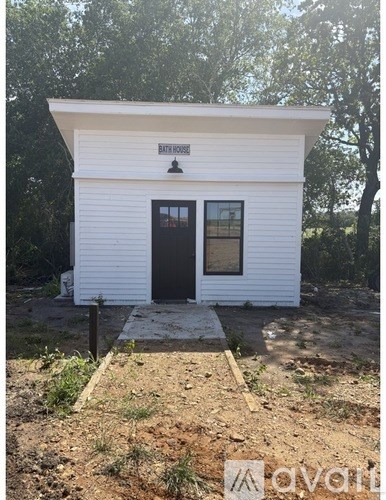 A small white building with a black door and windows is in the foreground.